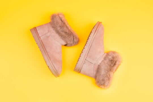 pair of fashionable winter ugg boots on yellow background, new pair