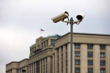 Fototapeta na wymiar Security cameras against the parliament building of Russia with russian flag. Video surveillance and privacy issues concept