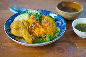 Biryani with chicken. Traditional Indian dish of rice and chicken marinated in spices and yoghurt.Top view. natural wooden background. Authentic Chicken Biryani served in a bowl or plate over colourfu
