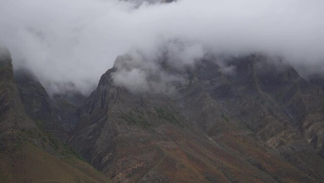4K shot of fog around the mountain peaks during the stormy weather at Tandi in Lahaul Spiti district at Himachal Pradesh, India. Clouds rolling over the peaks of the mountain. Nature background. 