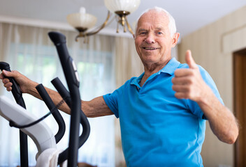 Senior man with elliptical trainer at home - obrazy, fototapety, plakaty