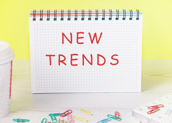 NEW TRENDS text written on a sheet of a notebook in a check on a yellow background