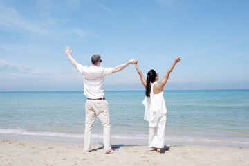 Young couple standing at the beach with their arms extended love concept travel.