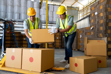 Warehouse workers work in teams and lift sealed cardboard boxes for shipments in large warehouses.