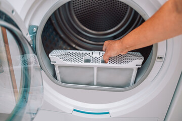 Housewife cleanup lints and dirt from tumble dryer filter. Clothes dryer lint filter that is...