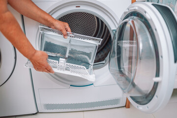 Housewife cleanup lints and dirt from tumble dryer filter. Clothes dryer lint filter that is...