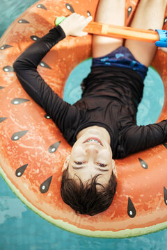 Teenage boy in a swimming pool on a float
