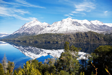 panorama of lago gutierrez with the mirrored lake on a sunny day, mountains with green forests. Snowy cathedral hill in the background