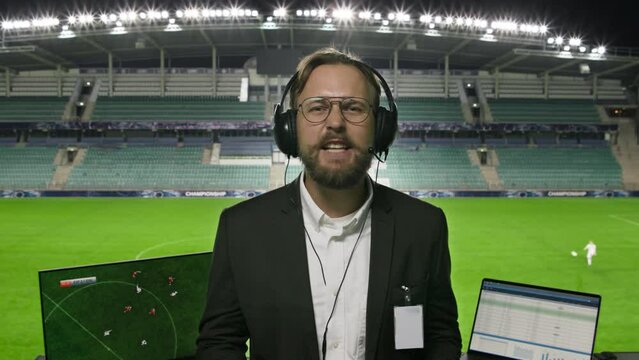 Portrait of Sports Commentator Analysing Soccer Match. POV Shot: Professional Announcer with Football Stadium and Field Behind Him Commenting on the Seasons Best Moments, Talking about Top Players