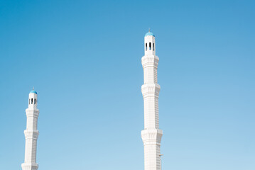 White high beautiful minarets of the mosque for the call to prayer against the backdrop of a clear...