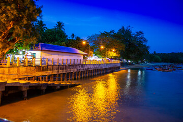 Fototapeta premium Pier at night with yellow lights on a background of blue sky