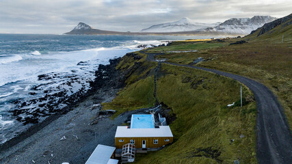 aerial view on gethermal pool in  Krossneslaug with fjords on background on the icelandic coast with storm and green grass