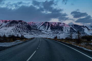 icelandic road with snowy mountains and rose peaks during sunrise