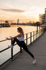Beautiful woman in sport suit for fitness makes stretching exercises on the street