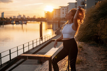 Fototapeta na wymiar Caucasian woman in sport clothes for fitness relaxing after exercises on the street during the sunset
