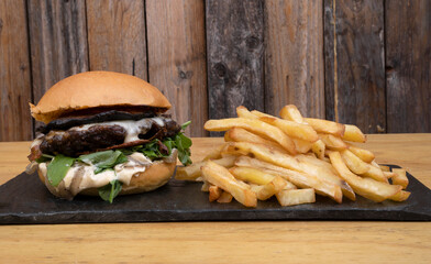 Delicious burger. Closeup view of a hamburger with raclette cheese, arugula, mayonnaise, mushrooms and french fries.