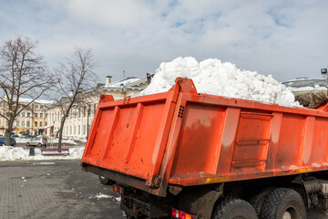 Tractor loader machine uploading dirty snow into dump truck. Cleaning city street, removing snow...
