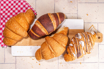 Freshly baked croissants with coffee espresso cup on beige tiled background top view copy space
