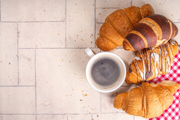 Freshly baked croissants with coffee espresso cup on beige tiled background top view copy space