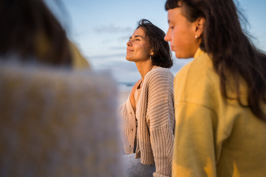 Three happy female friends smiling and enjoying of the perfect sunset together