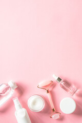 Skin care product, cream, soap serum, jade roller. Natural cosmetics on pink. Flat lay image with copy space.