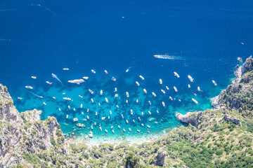 Fototapeta na wymiar Looking down at a cove of the bright blue waters of the Mediterranean Sea with boats at anchor on a bright sunny day.