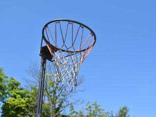 Basketball netted ring on blue sky background.