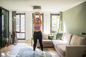 Full length view of the positive woman stretching arms and warming up