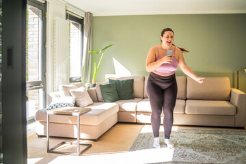 Overjoyed woman singing in smartphone like at microphone and dancing