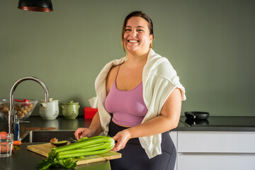Laughing lovely overweight woman preparing vegetables for the future breakfast on chopping board