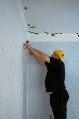 Construction worker plastering and smoothing concrete wall in room. Application of thermal insulation.