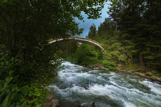 abandoned stone arch bridge and river in mountains