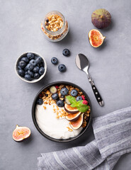 Natural yogurt with granola, berries and figs  in a bowl on a blue background. Healthy and nutritious breakfast. Diet food.