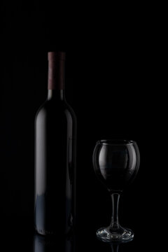 red wine bottle with glass on black mirror background