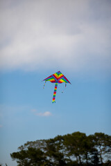 kite against a blue sky. Multicolored kite. The colors of the rainbow. Kite soaring in the air