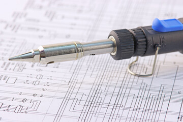 Electric soldering iron close-up on an electronic diagram.Soft focus.