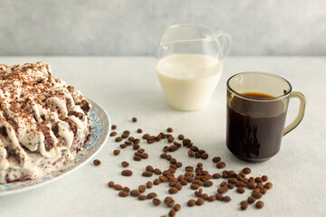 Coffee with cream in a glass mug with coffee beans, cream cake. Drink on a light gray background.