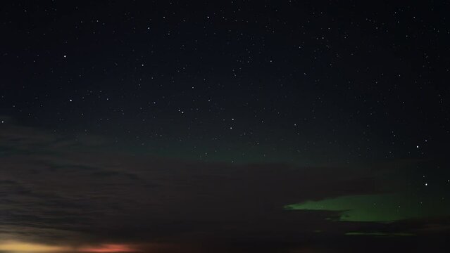 Aurora Borealis (Northern Lights) appearing on the night sky filled with stars after sunset. Time Lapse. 
