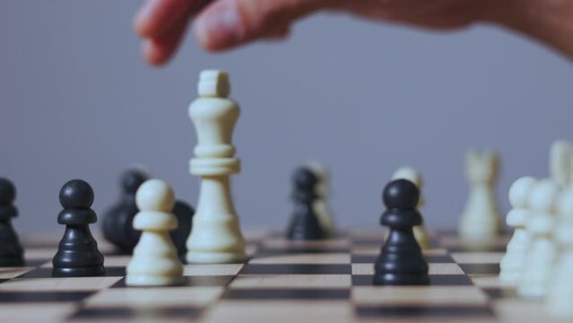 Close up and 4K of hand picking the king chess to kill the enemy king to win the game. It shows concept of competition with strategic business planning of teamwork for winning the battle.