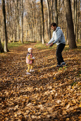 Fototapeta premium Father play with baby daughter in family leisure at autumn activity in forest.