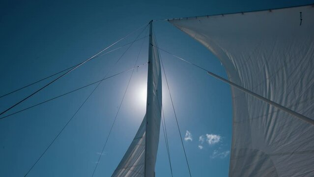 Sails Of Catamaran Billowing In The Wind, Against Blue Sky. Sun Partially Behind The Sail. Punta Cana Catamaran