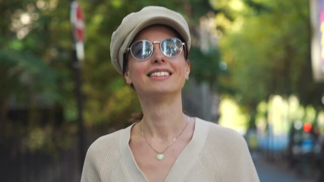 Young attractive girl in a cap and sunglasses walking on an autumn street