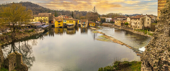 Fototapeta na wymiar Extra wide High angle view of Borghetto sul Mincio with the buildings reflecting on the water at sunset
