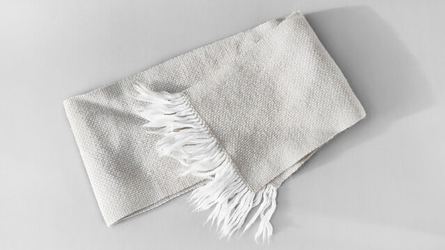 Comfortable knitted wool gray winter scarf with tassels on a gray background.