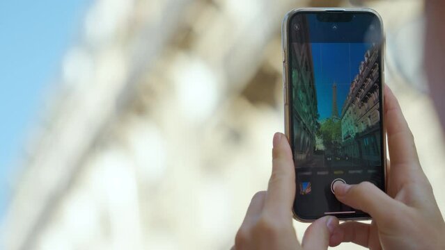 Female hands taking photo of the Eiffel Towers on a smartphone