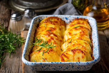 Potato gratin - graten (baked potatoes with cream and cheese) with rosemary and forks (Turkish...