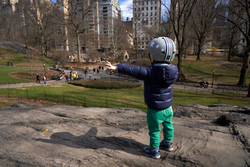 a little boy in central park wearing a helmet - obrazy, fototapety, plakaty