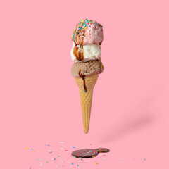 funny creative concept of flying wafer cone with ice cream covered, strewed sprinkles and poured with chocolate icing on pink