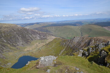 a view looing down in the crater of Cadair Idris with a mountain view behind it