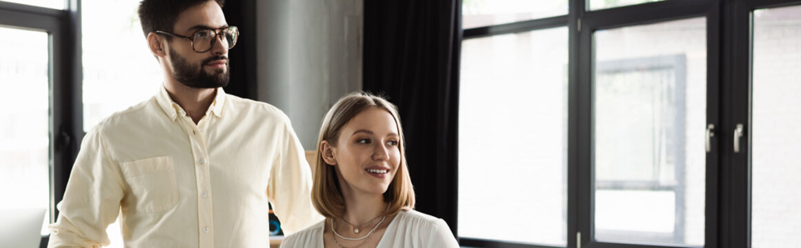 Businessman and intern looking away in office, banner.